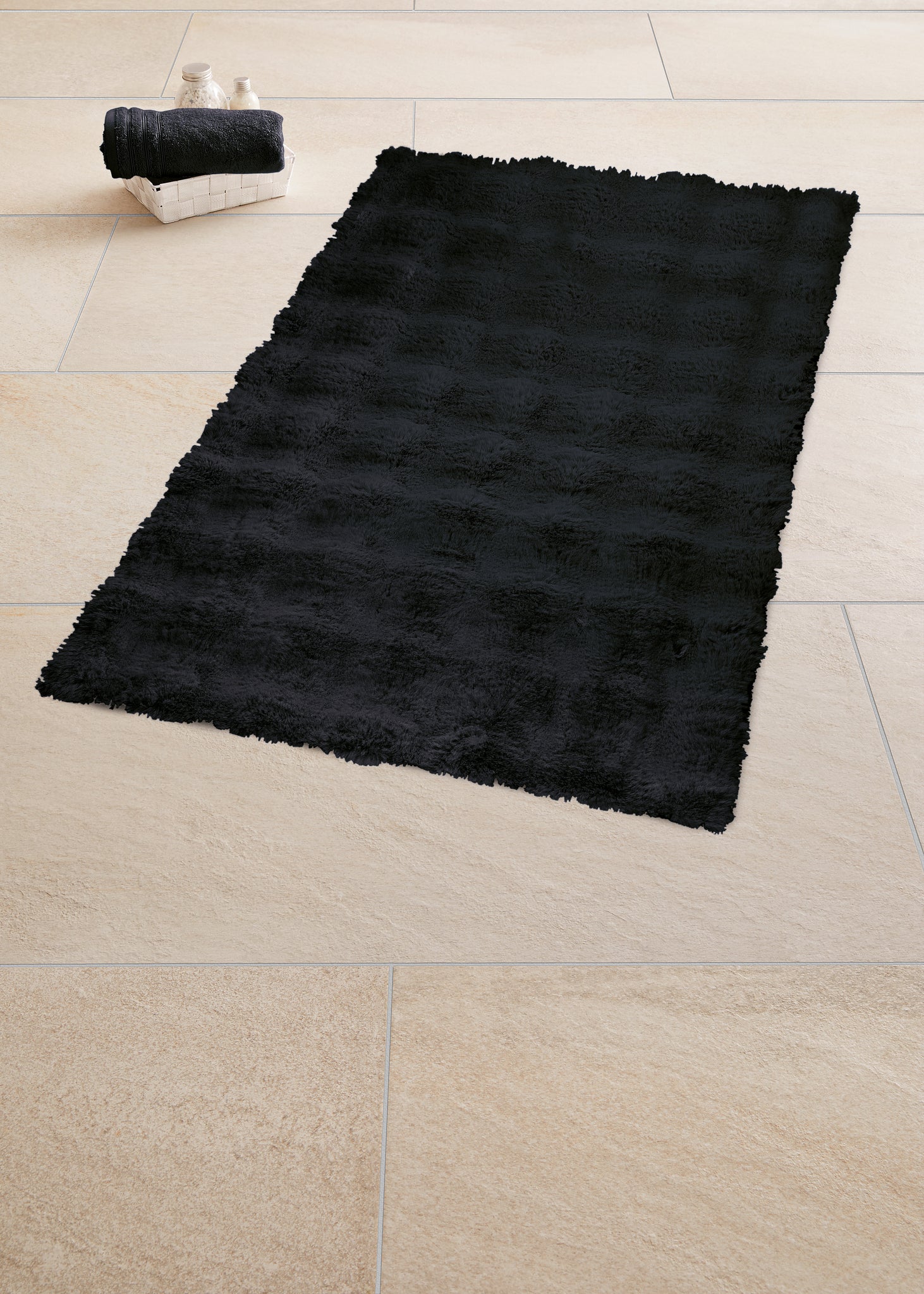 Schwarzer Badteppich CLOUD 50 x 60 cm liegt auf hellen Fliesen im Badezimmer.