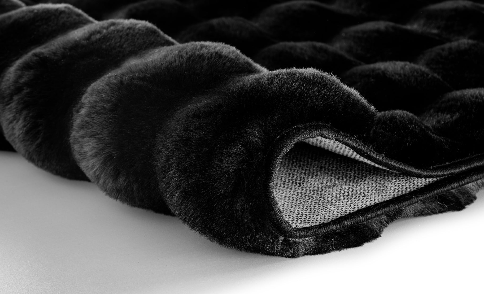 Schwarzer Badteppich CLOUD 70 x 120 cm liegt weich gefaltet auf hellem Untergrund.