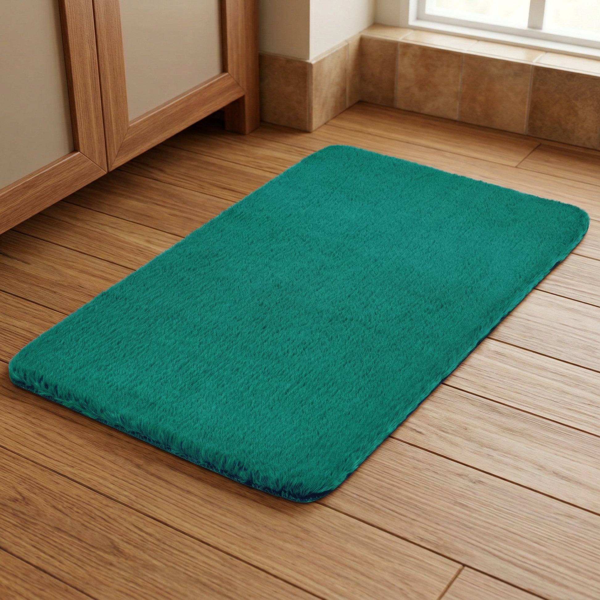 Türkisfarbene Badematte auf Holzfußboden vor großem Schrank am Fenster