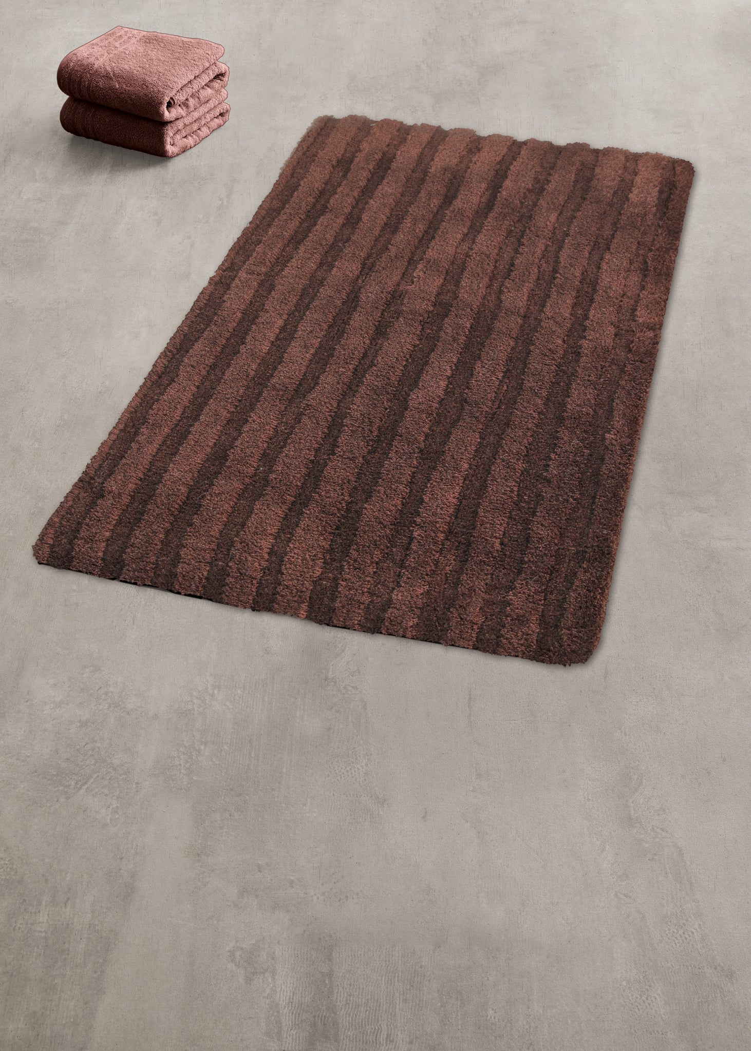 Brauner gestreifter Badteppich auf Betonboden mit gefalteten Handtüchern
