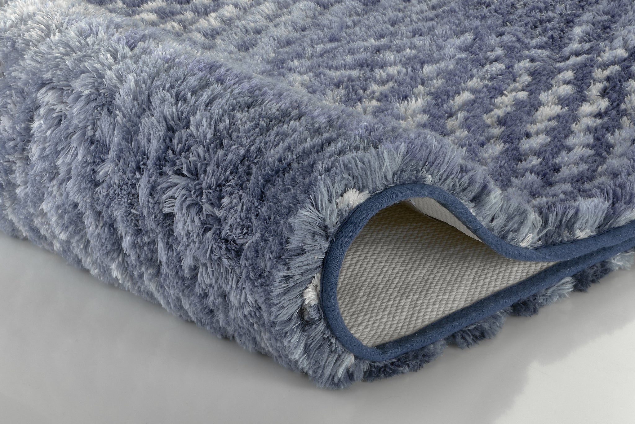 Blaue, flauschige Badematte in Nahaufnahme mit rutschfester Rückseite