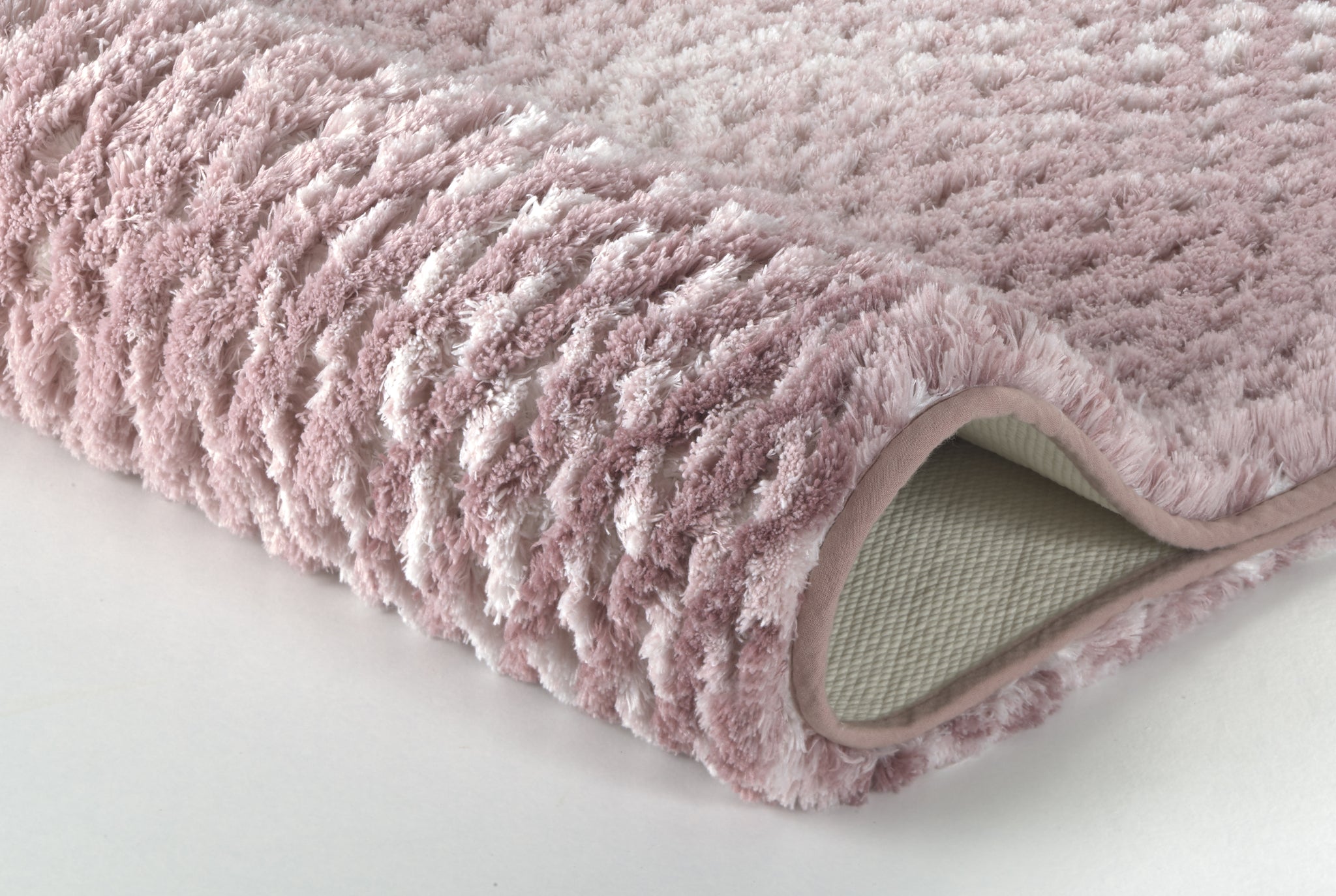 Nahaufnahme einer rosa, flauschigen Badematte auf weißem Hintergrund