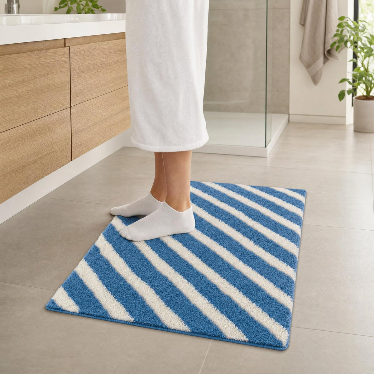 Person steht im Bad auf blau-weiß gestreiftem Teppich vor der Dusche.