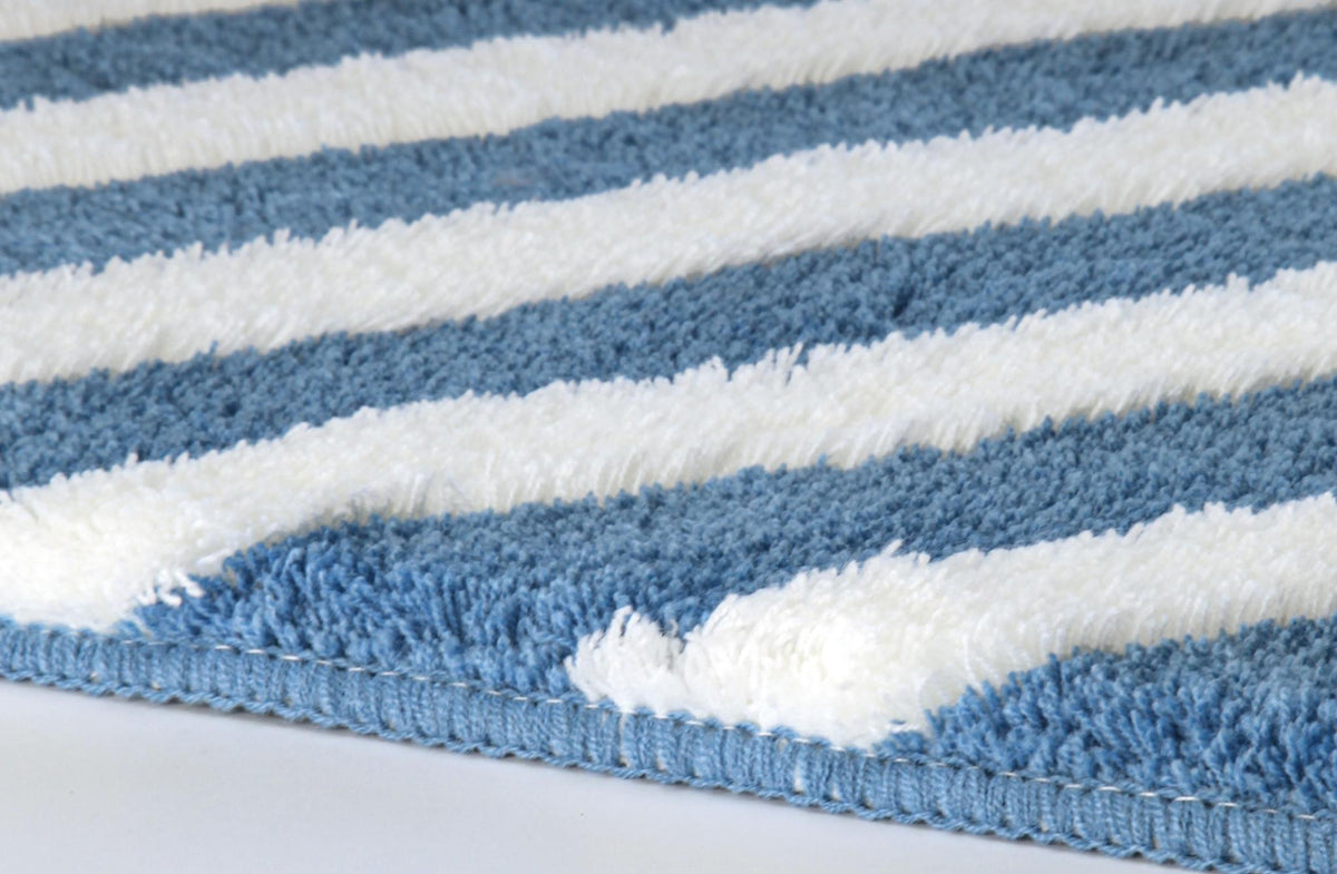 Blau-weißer flauschiger Teppich mit breiten Streifen in Nahaufnahme.