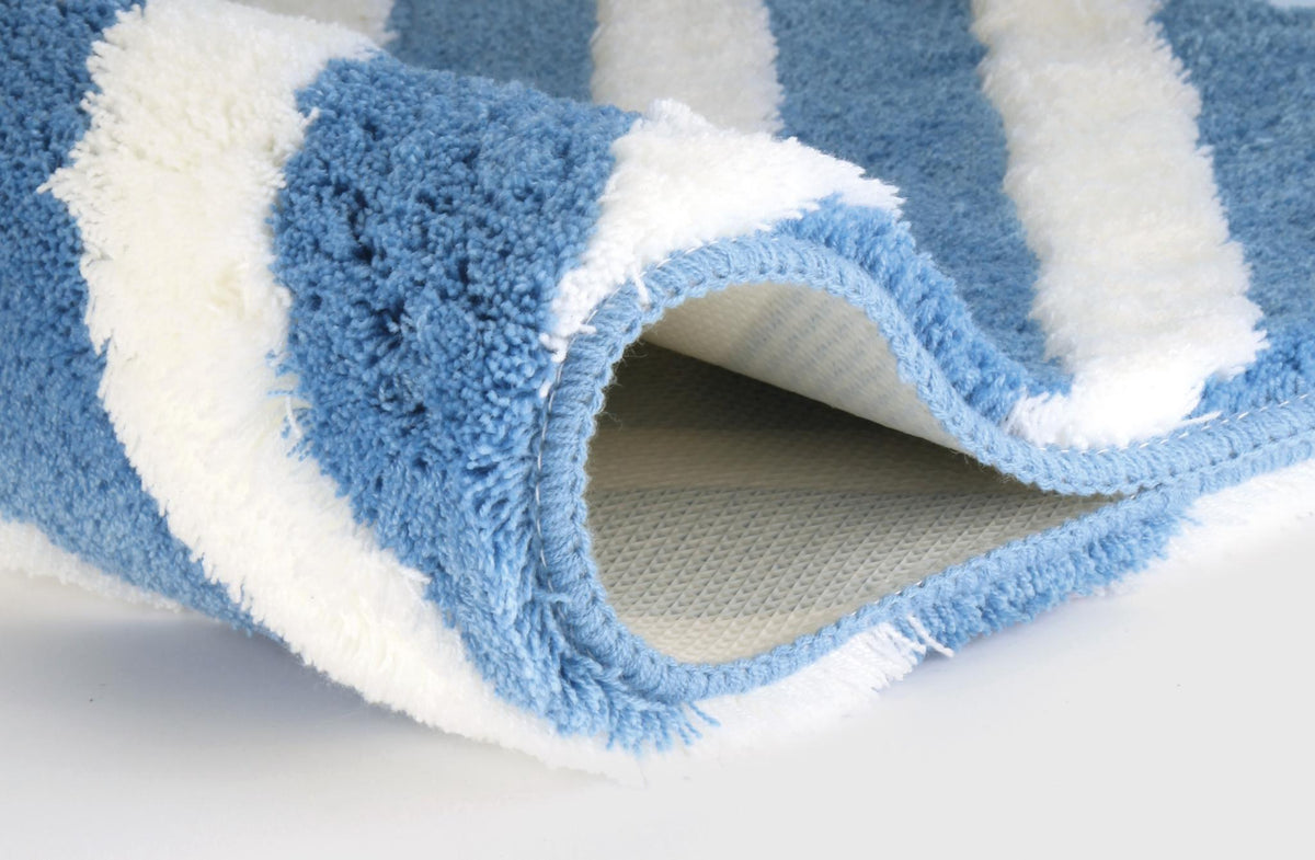 Blau-weiß gestreifter, flauschiger Teppich mit umgeschlagener Ecke.