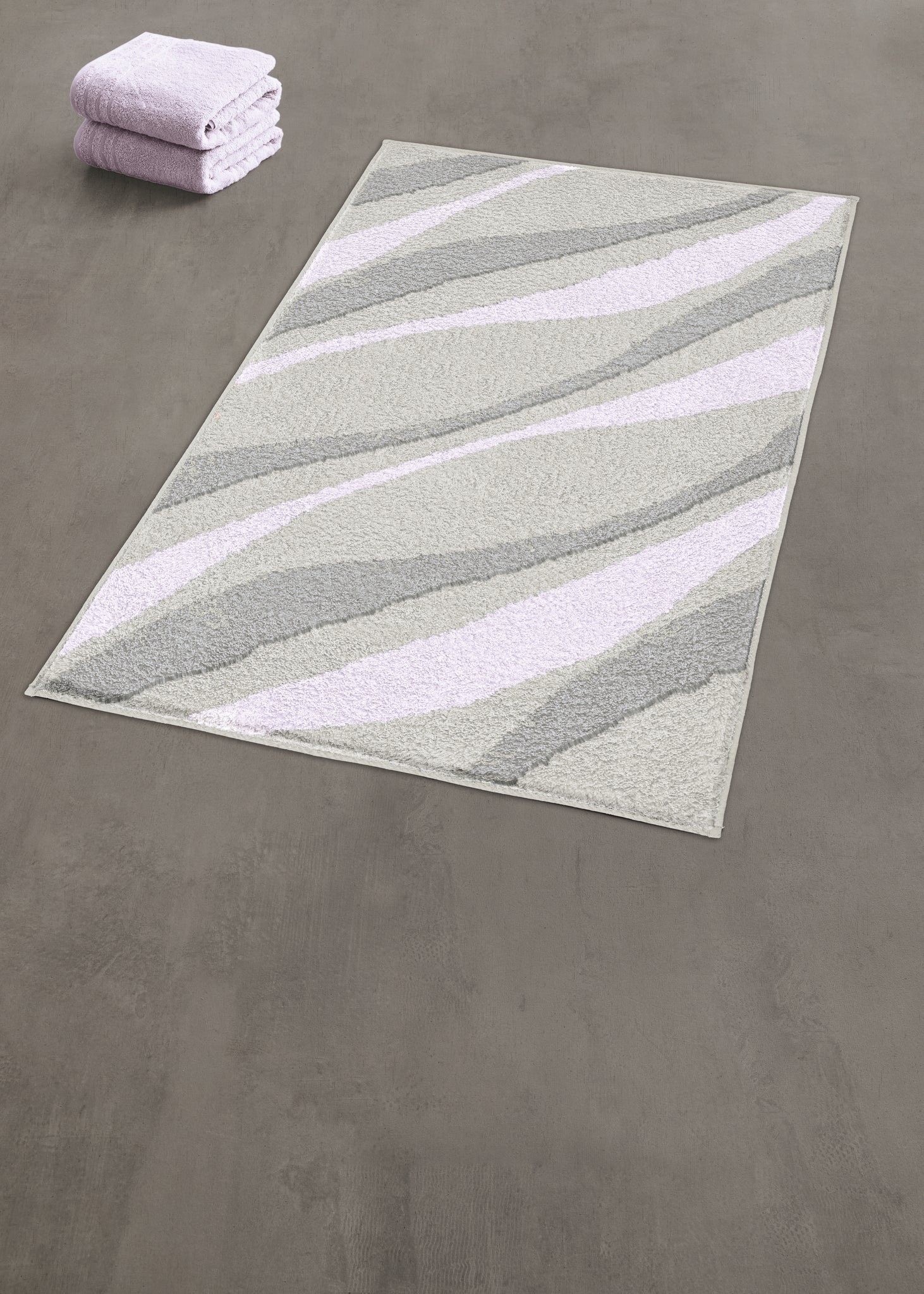 Badteppich mit grauen und fliederfarbenen Wellen, gefaltete Handtücher