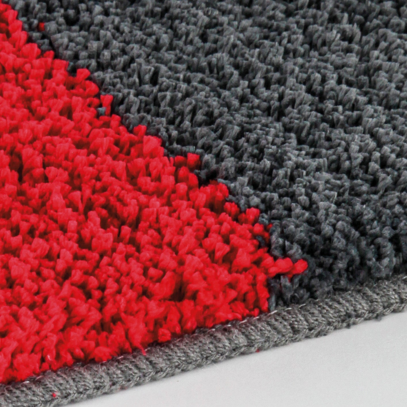 Badteppich DYNAMIC Rubin mit grauer und roter Hochflor-Struktur in Nahaufnahme.