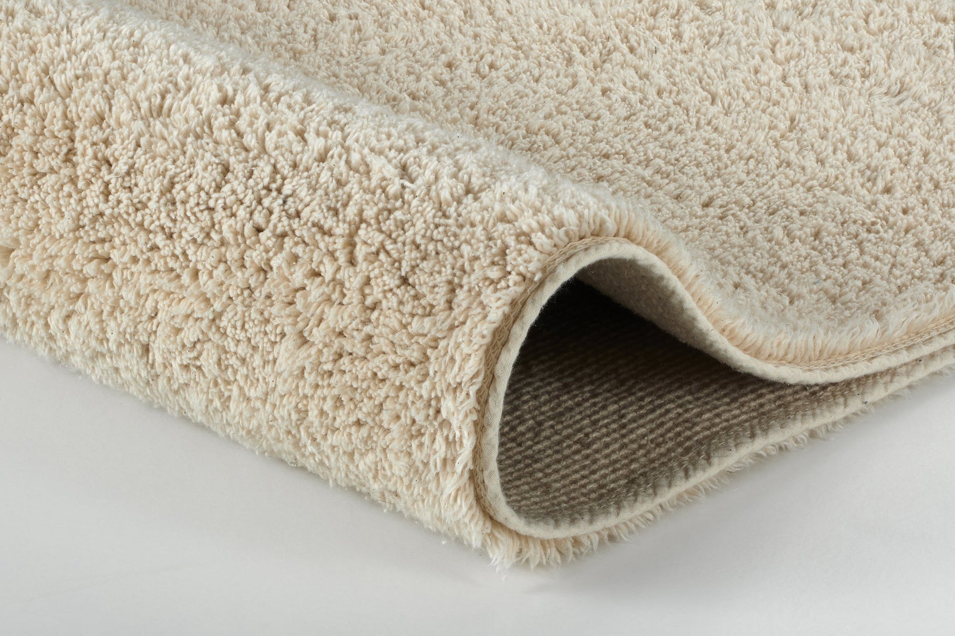 Beiger, weicher Badteppich aus Frottee, seitlich leicht aufgerollt