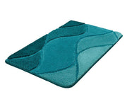 Badteppich FIONA in Petrol 60 x 100 cm mit geschwungenem Wellenmuster liegt auf dem Boden.