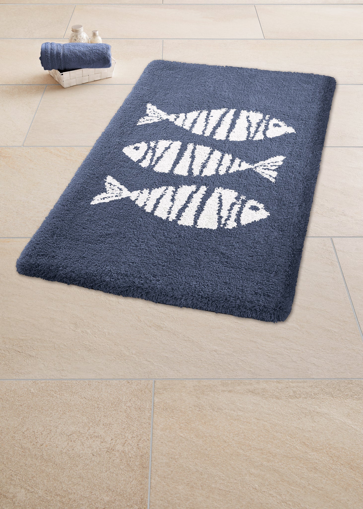 Dunkelblauer Badteppich mit drei weißen Fischmotiven auf Fliesenboden
