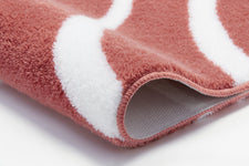 Nahaufnahme einer rosafarbenen Badematte mit weißen Wellenstreifen