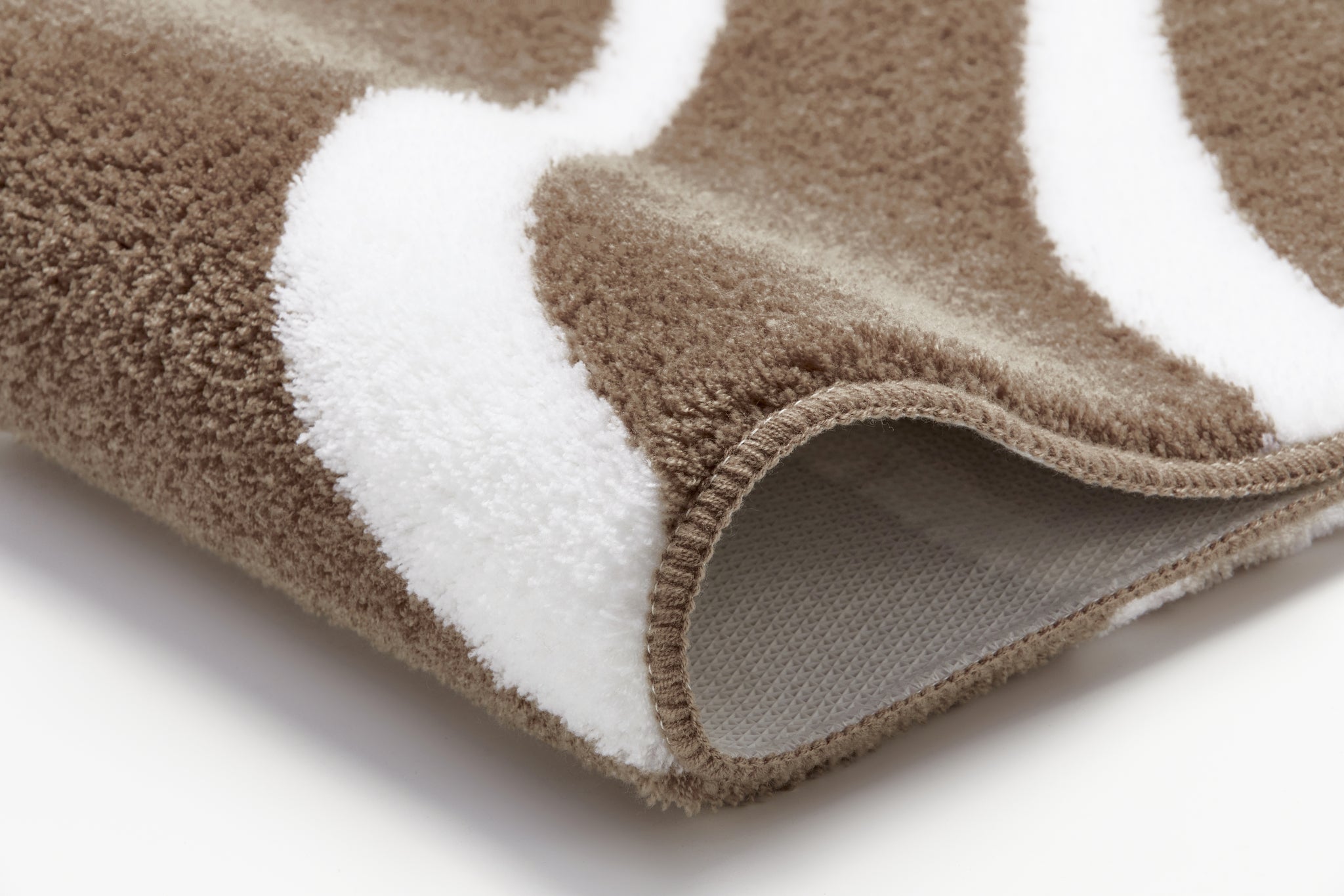 Nahaufnahme braun-weißer Badezimmerteppich mit weichem Flor aus Mikrofaser