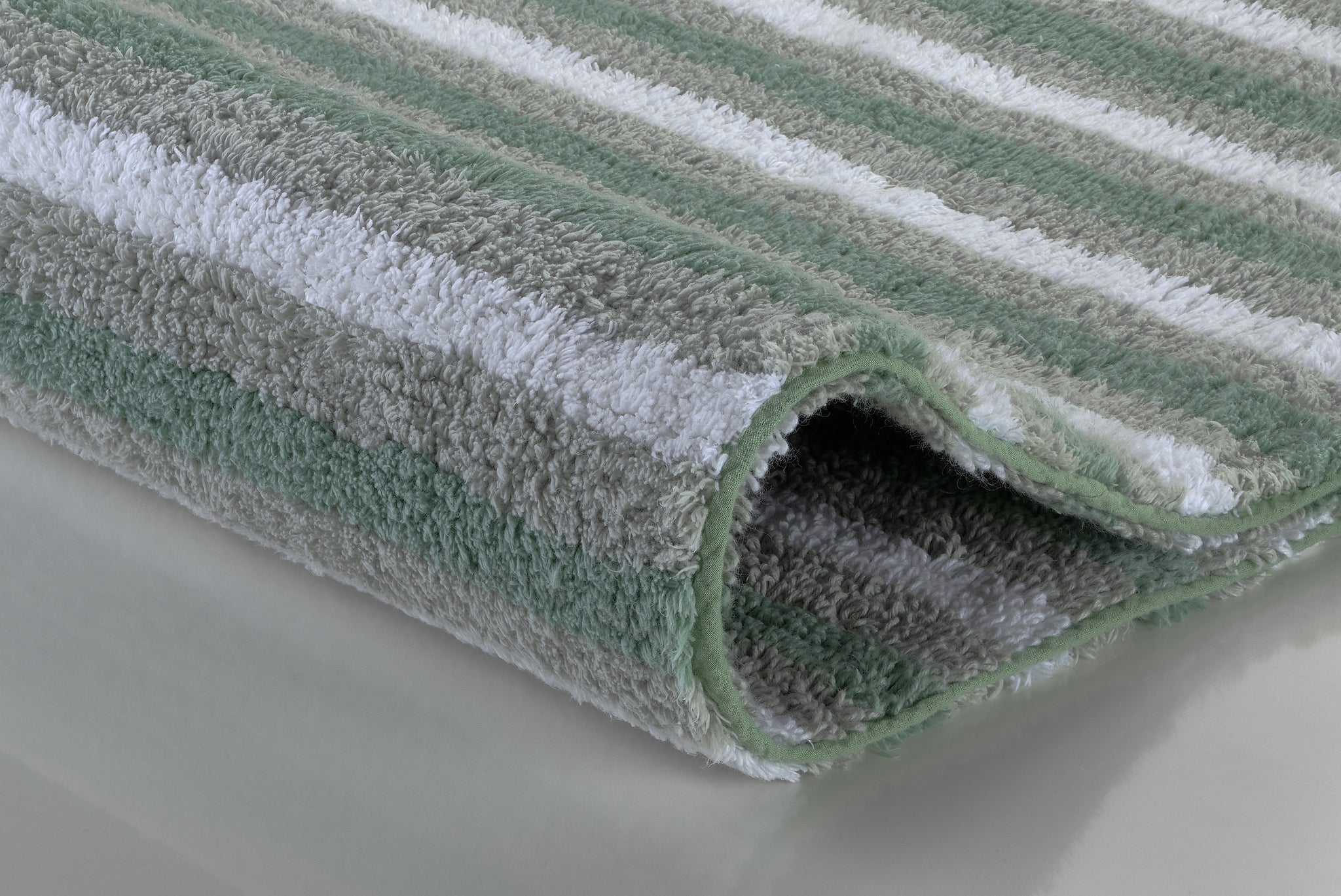 Nahaufnahme eines weichen Badteppichs mit grünen und grauen Streifen