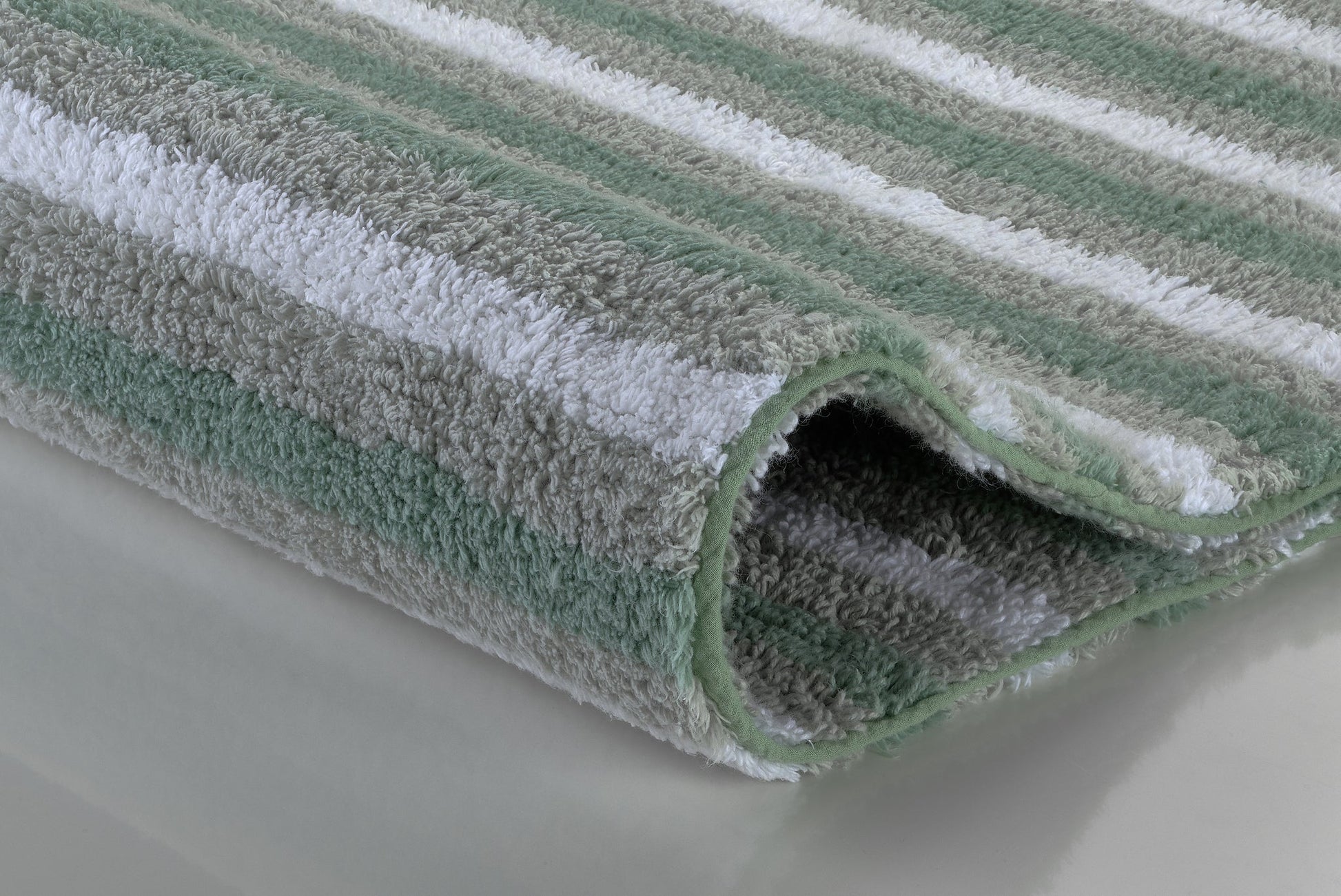 Gefaltete Badematte mit grünen, grauen und weißen Streifen, Nahaufnahme