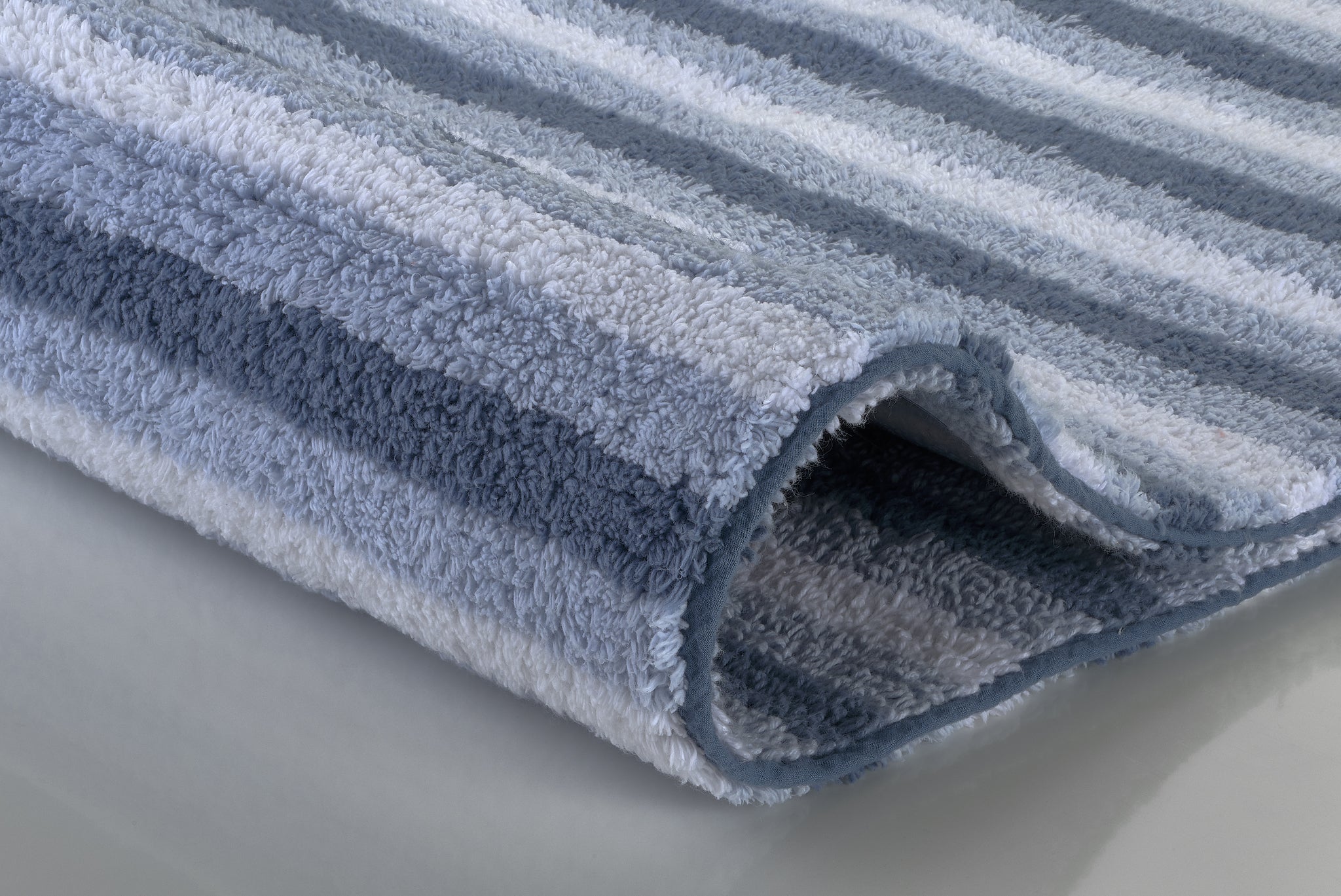 Gefalteter, flauschiger Badteppich mit blauen und weißen Streifen