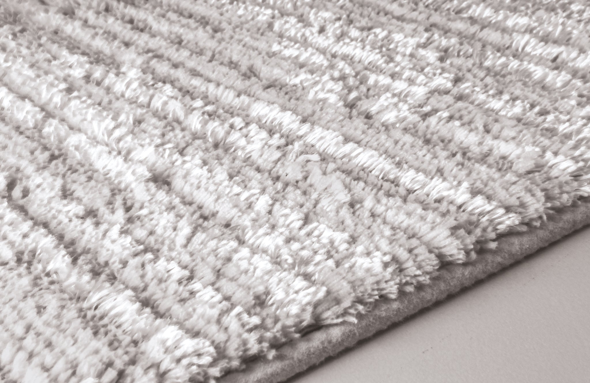 Nahaufnahme einer hellgrauen, flauschigen Badematte mit Struktur Oberfläche