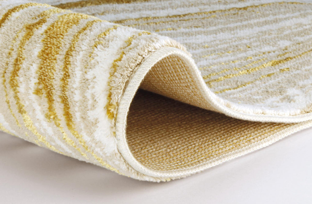 Gerollter cremeweißer Teppich mit goldfarbigem Linienmuster.