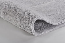 Hellgraue, weiche Badematte mit dichter Hochflor-Struktur in Nahaufnahme