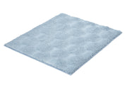 Hellblauer flauschiger Badteppich mit Wabenmuster auf Weiß.