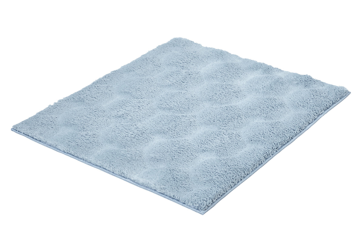 Hellblauer flauschiger Badteppich mit Wabenmuster auf Weiß.