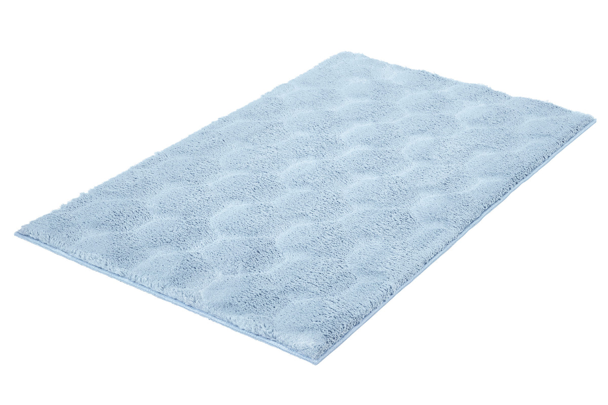 Hellblauer, flauschiger Badteppich in rechteckiger Form auf Weiß.