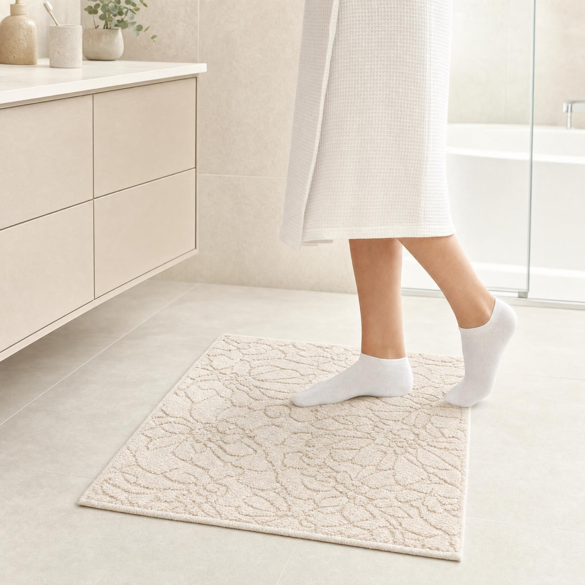 Cremefarbiger Badteppich mit floralem Muster in hellem Badezimmer.