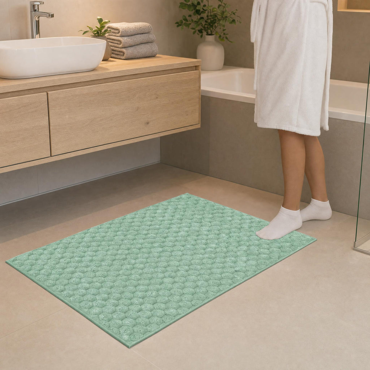 Mintgrüne Badematte in modernem Bad vor Waschbecken und Badewanne.