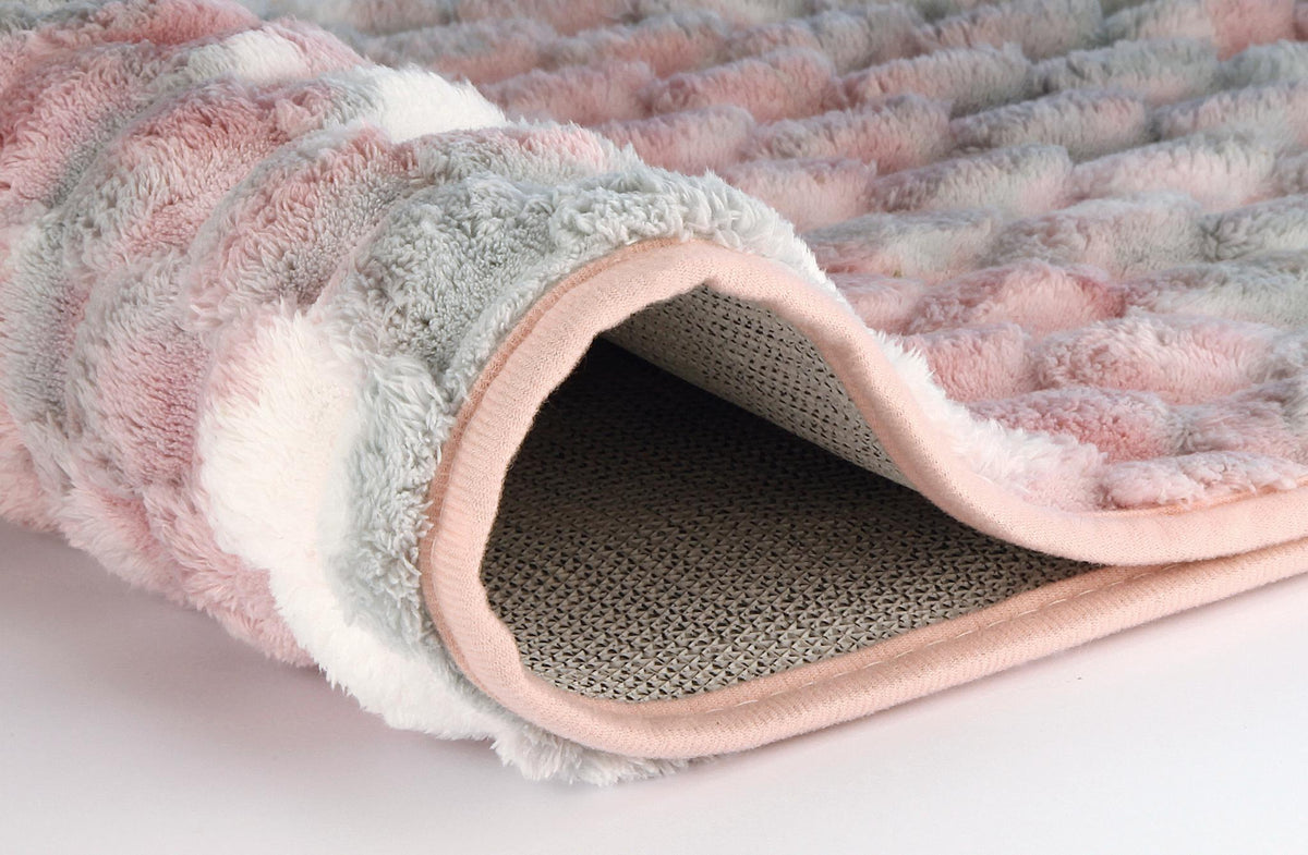 Nahaufnahme einer flauschigen rosa-grauen Decke mit rutschfester Unterseite.