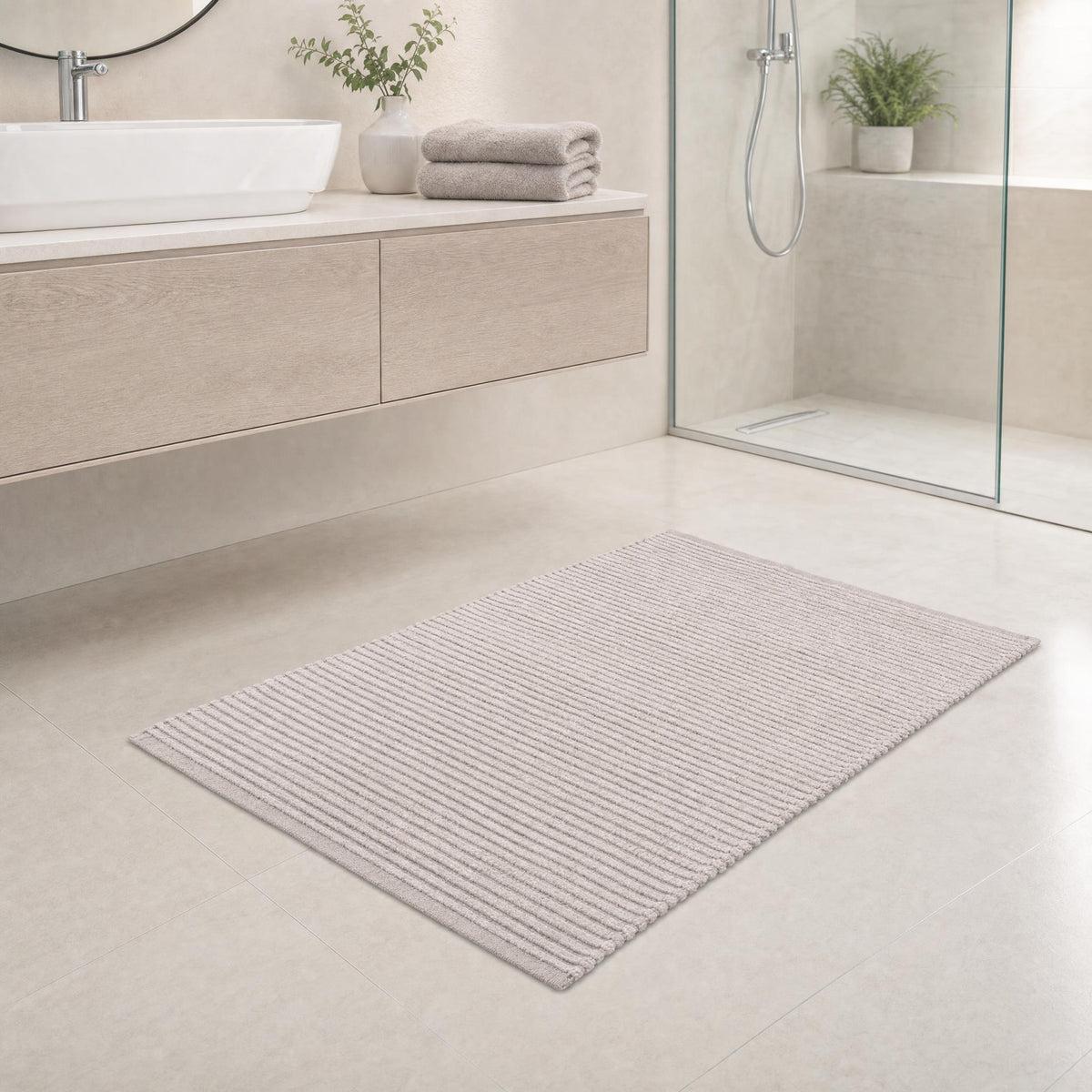 Heller Badteppich in modernem Bad vor Waschtisch und Glasdusche.