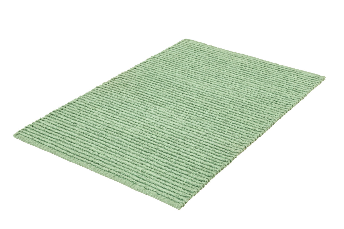 Grüner gerippter Badteppich in rechteckiger Form auf weißem Hintergrund.