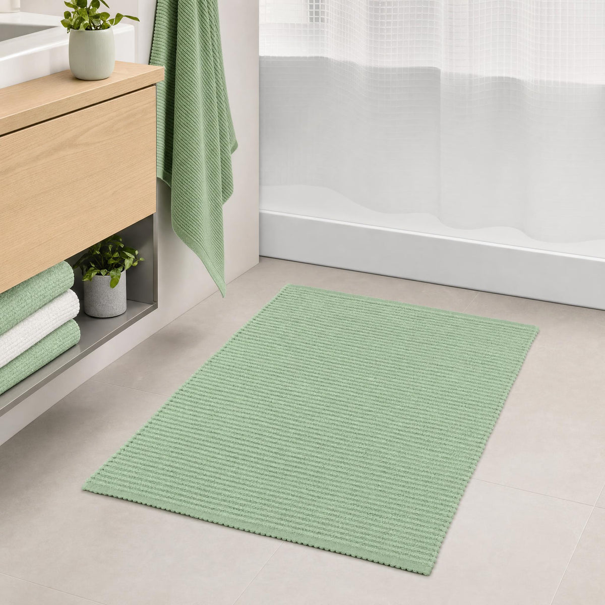 Grüner Badteppich vor der Dusche in hellem Badezimmer mit Handtuch.