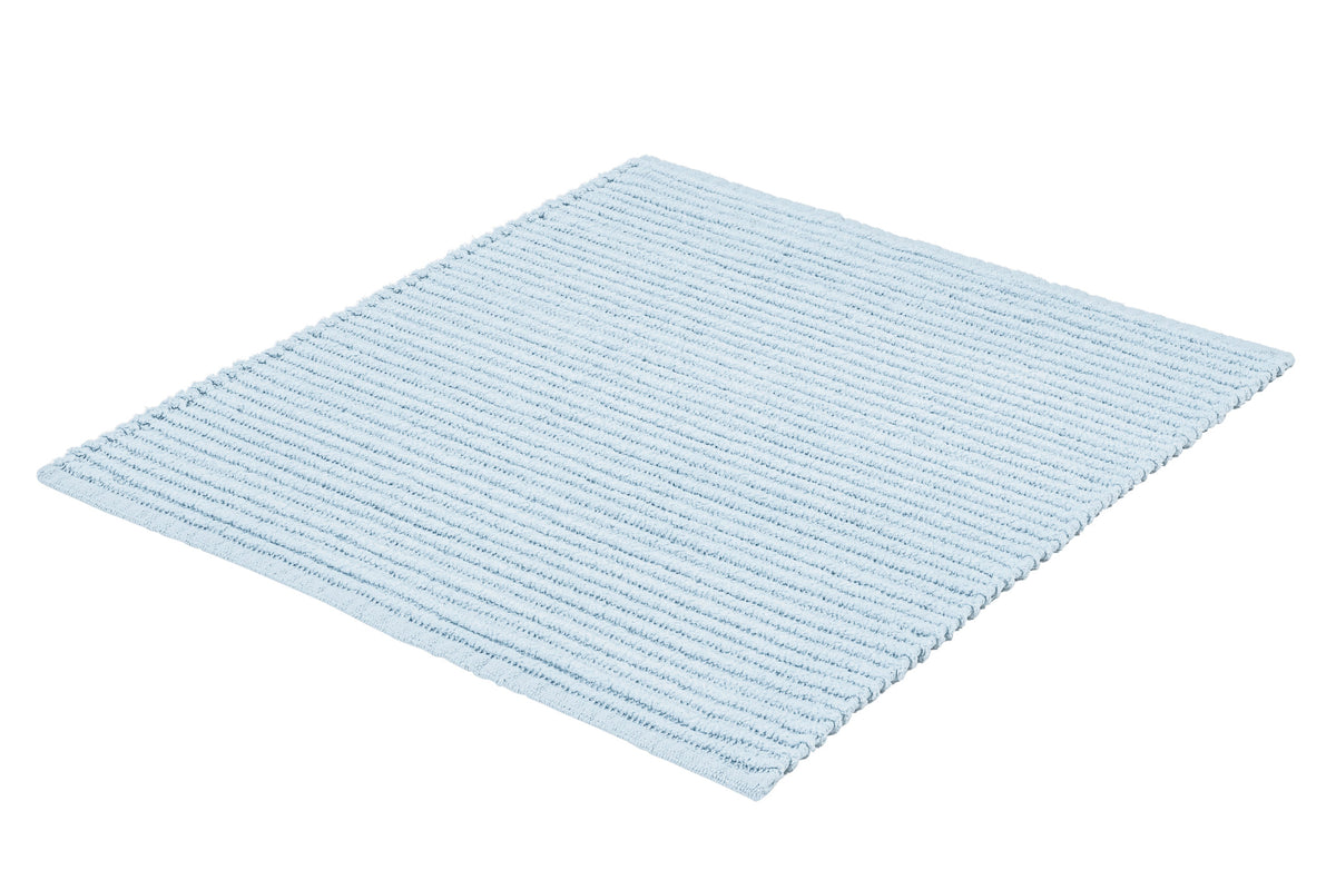 Hellblauer gerippter Badteppich in rechteckiger Form auf weißem Grund.