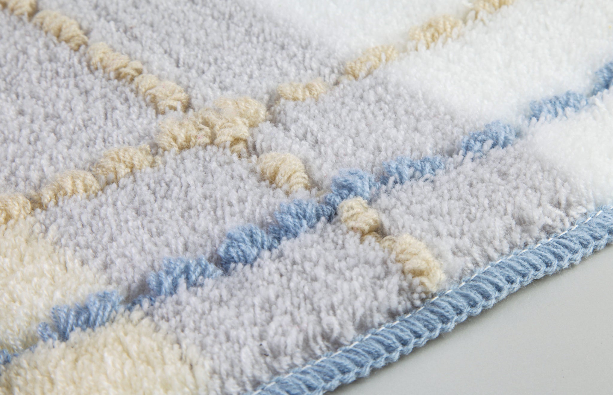 Nahaufnahme einer karierten Badematte aus Frottee in Blau, Beige, Grau