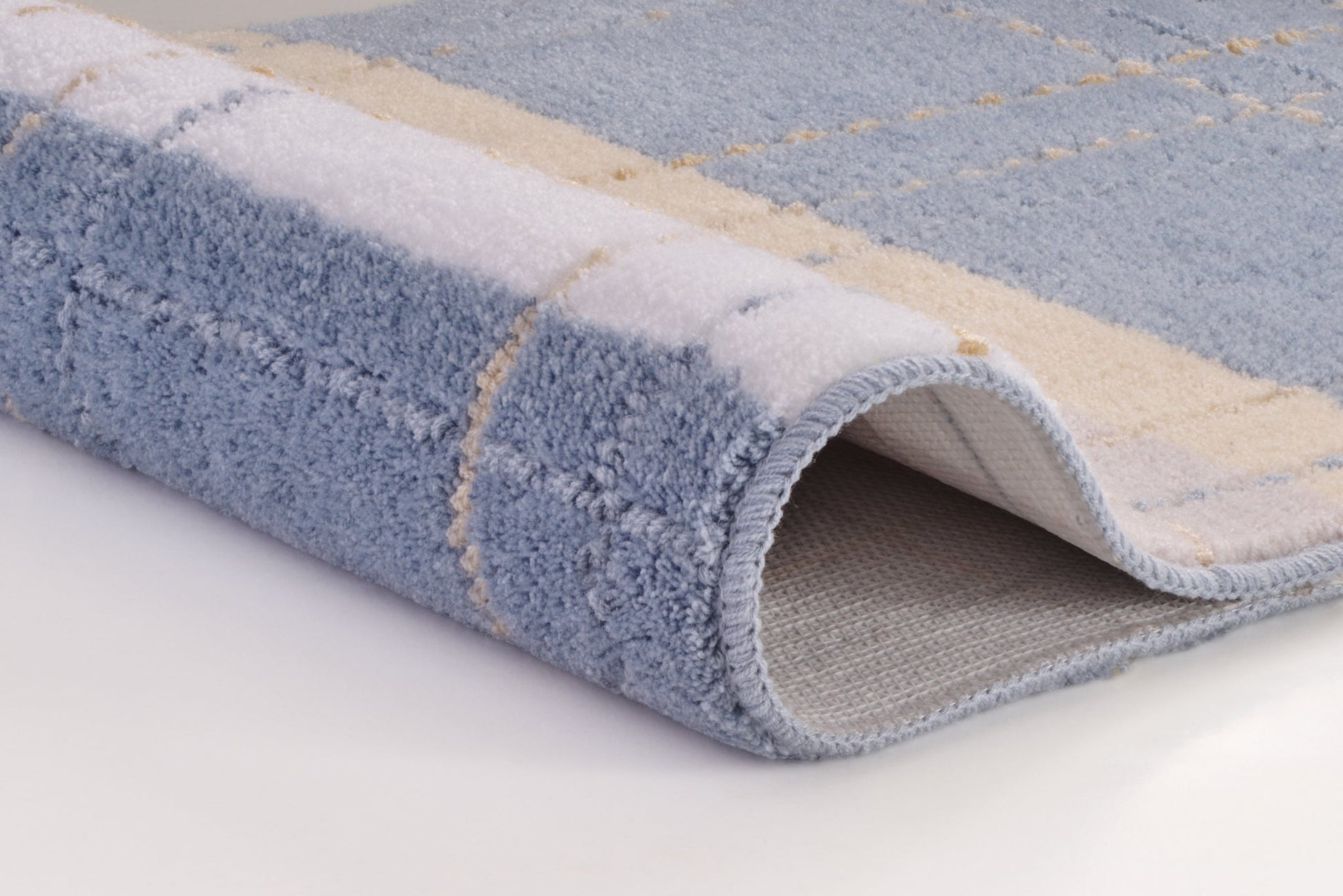 Nahaufnahme einer gefalteten, blau-beigen Badematte mit Karomuster
