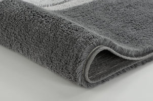 Graue Badematte aus Hochflor im Detail, seitlich leicht aufgerollt