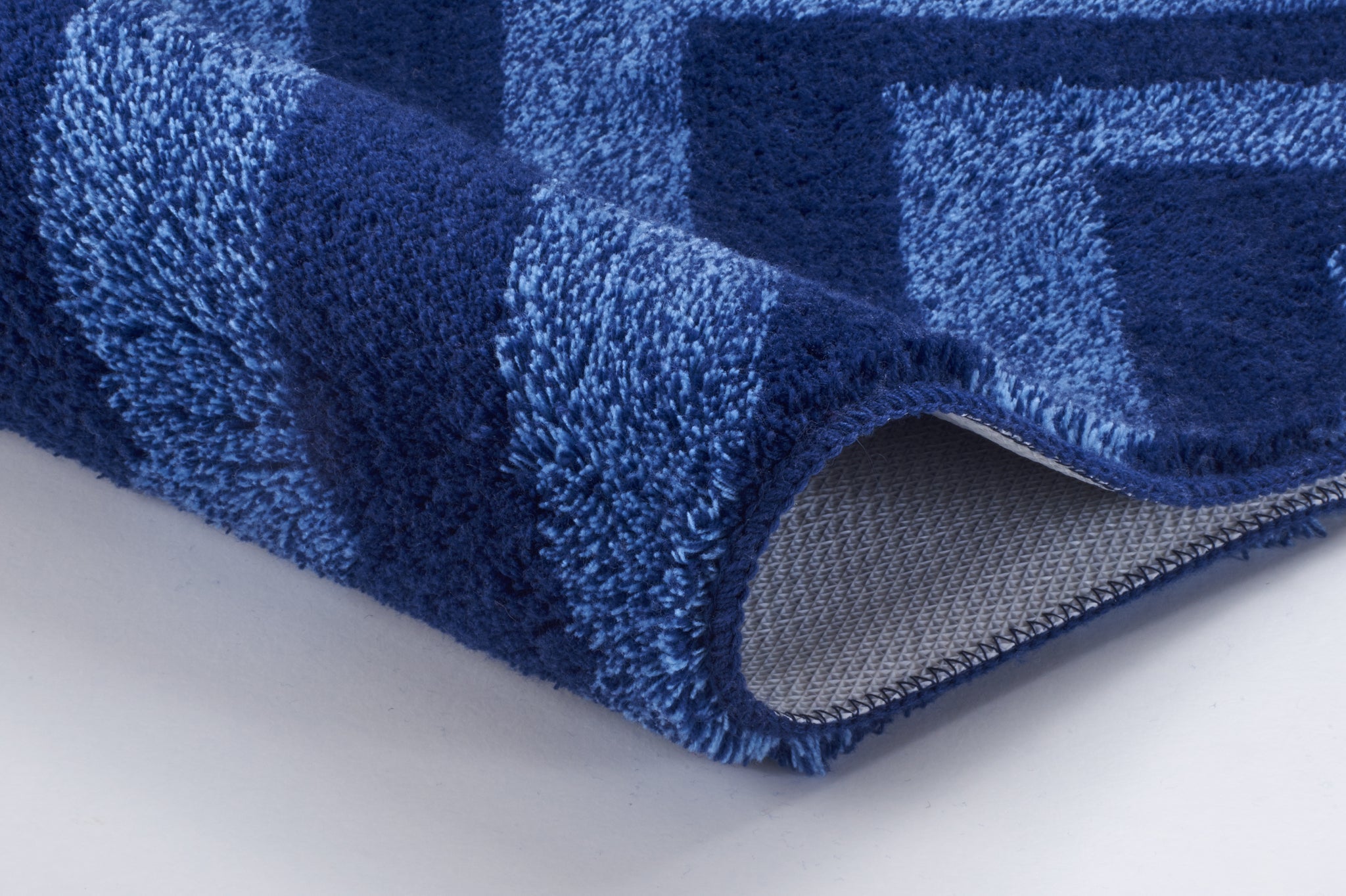 Blaue Badematte mit breiten Streifen, eine Ecke leicht umgeschlagen