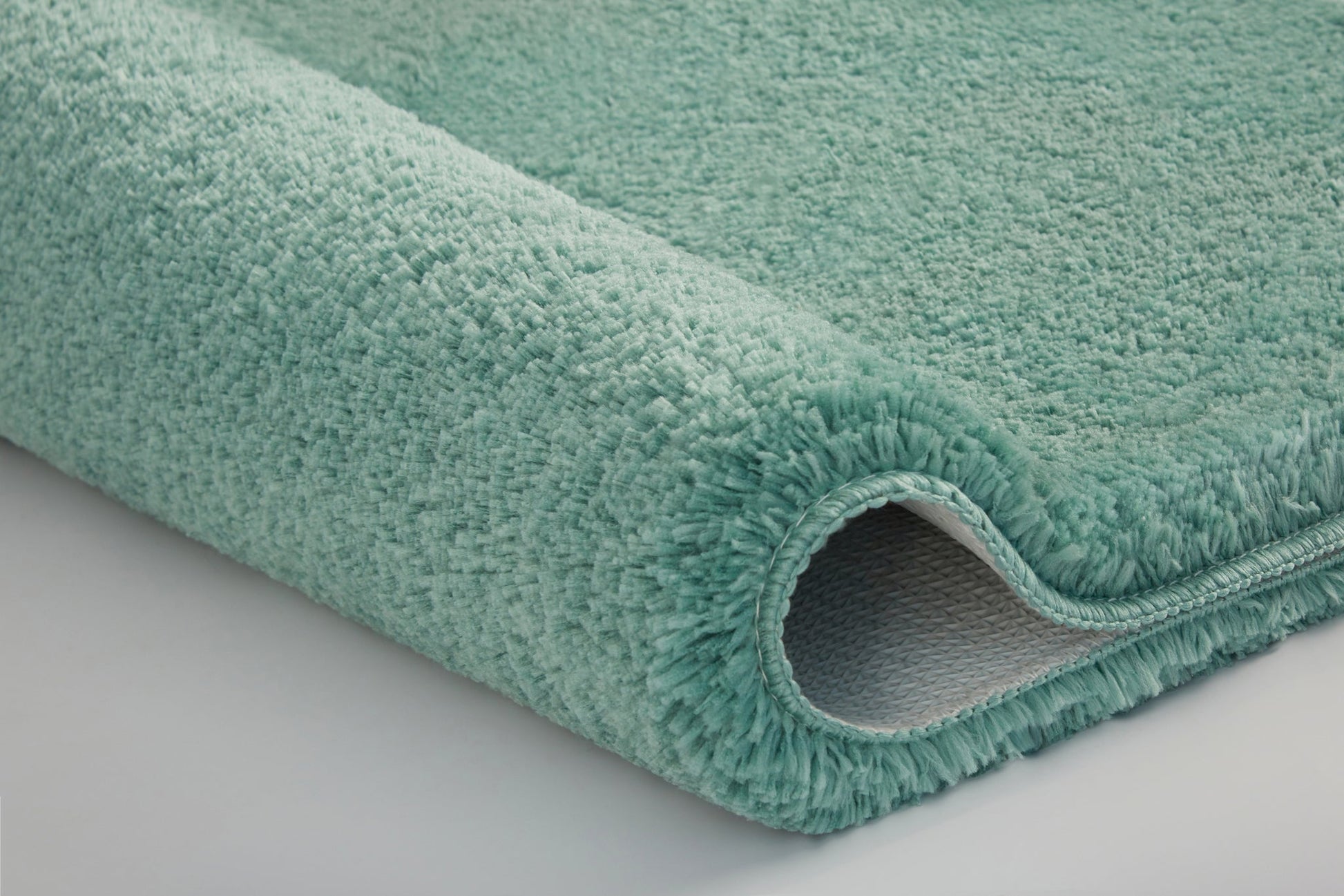 Nahaufnahme einer mintgrünen Badematte mit weichem, dichten Teppichflor