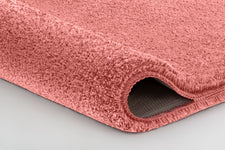 Detailaufnahme einer rosafarbenen Badematte mit abgerundeter Kante