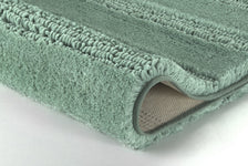 Detailaufnahme einer mintgrünen Badematte mit umgeschlagener Ecke