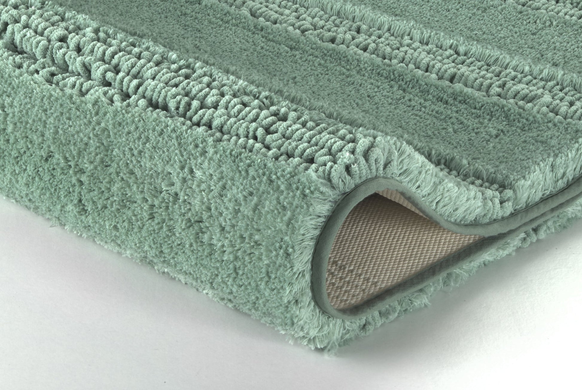 Nahaufnahme einer mintgrünen Badematte mit umgeschlagener Ecke unten
