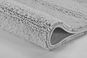 Detailaufnahme einer hellgrauen Badematte mit weicher Schlaufenstruktur