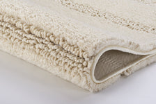 Gefaltete beige, weiche Badematte mit rutschfester Unterseite aus Gummi