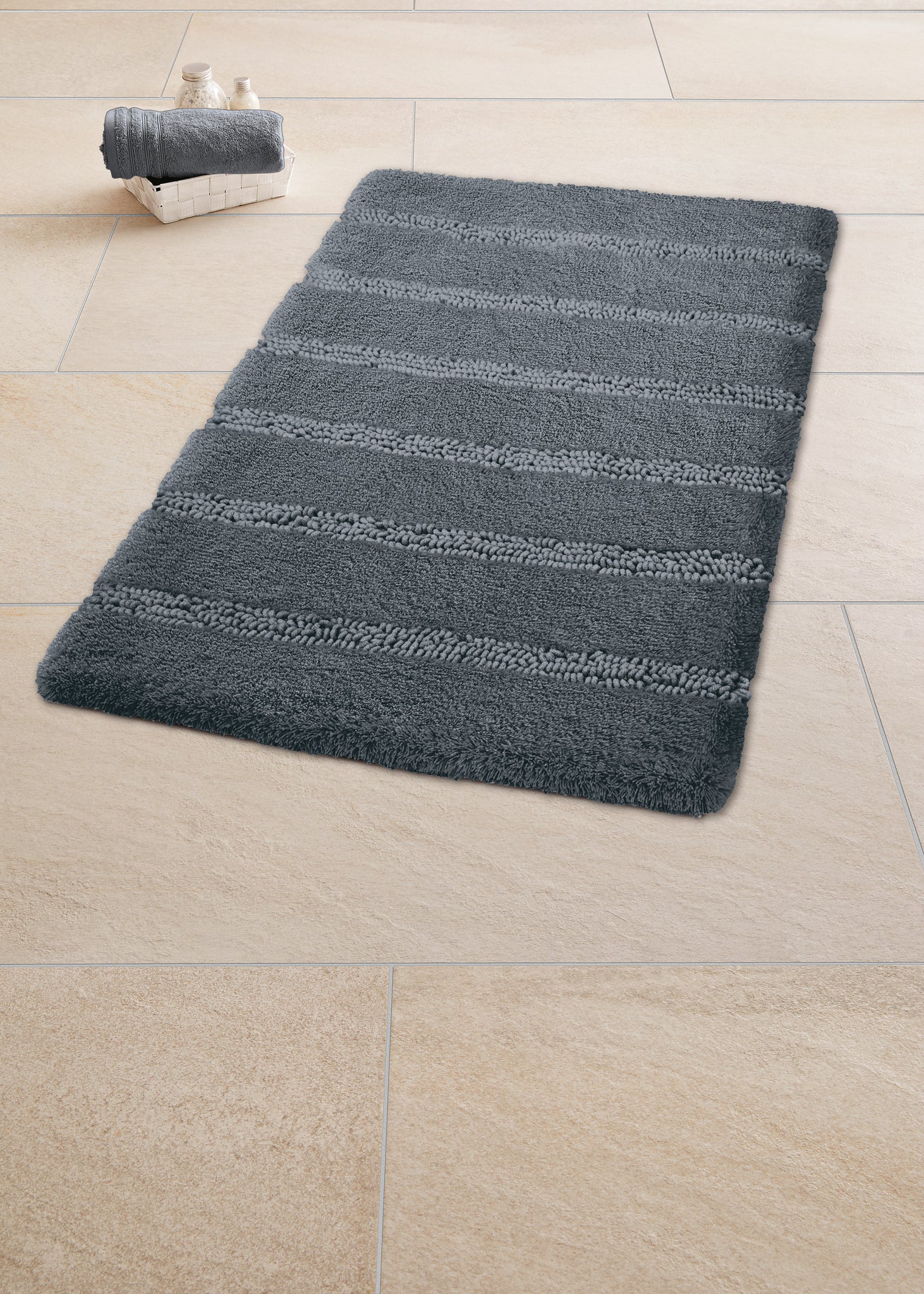 Graue Badematte mit Streifenmuster auf beigem Fliesenboden im Bad