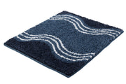 Badteppich MOVE Iceblue 50 x 60 cm mit weißen Wellenlinien liegt auf hellem Untergrund.