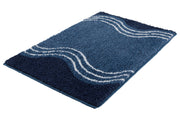 Badteppich MOVE Iceblue 65 x 115 cm mit Wellenmuster in Blautönen liegt auf dem Boden.