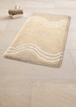 Beiger Badematte mit weißen Wellenlinien auf großem hellem Fliesenboden