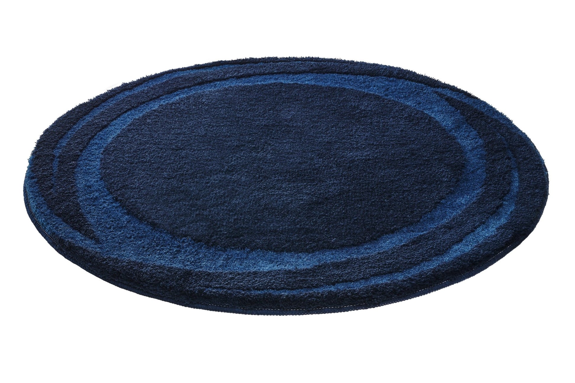 Runder Badteppich MYSTIC Navy mit blauem Kreisdesign liegt auf hellem Untergrund.