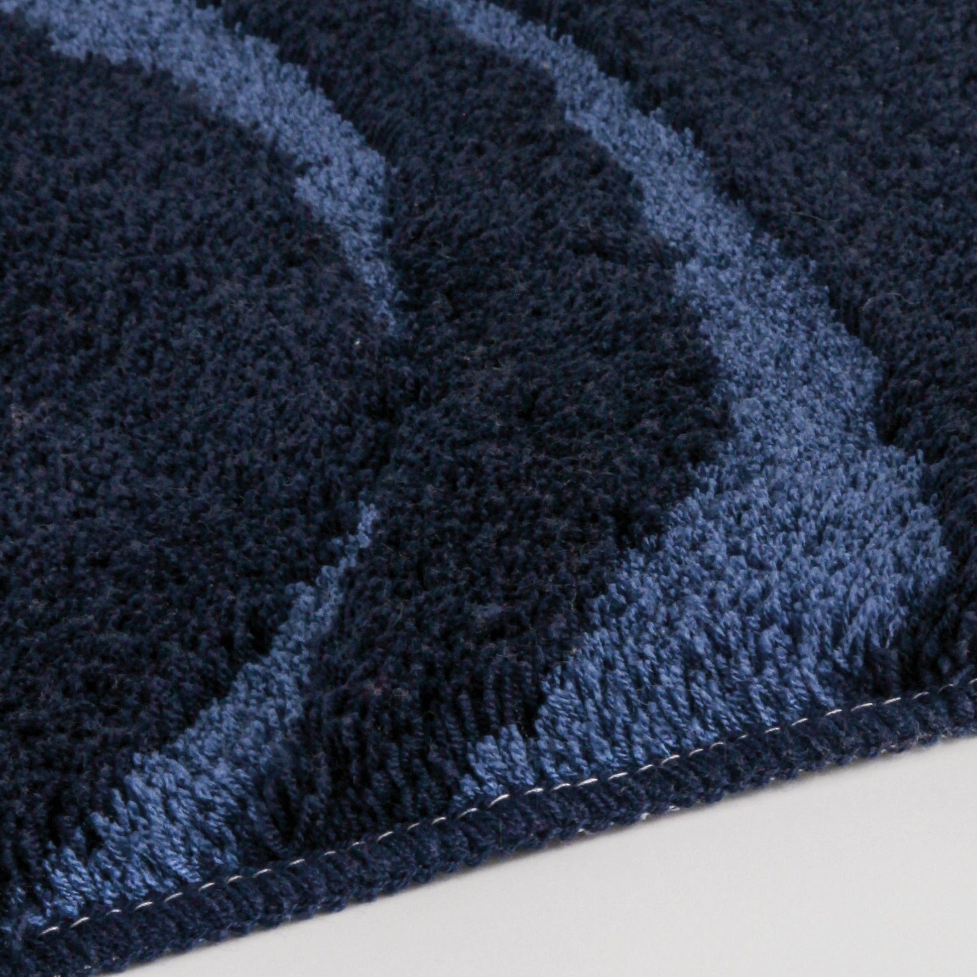 Nahaufnahme des runden Badteppichs MYSTIC Navy 100 cm mit geschwungenem Muster.