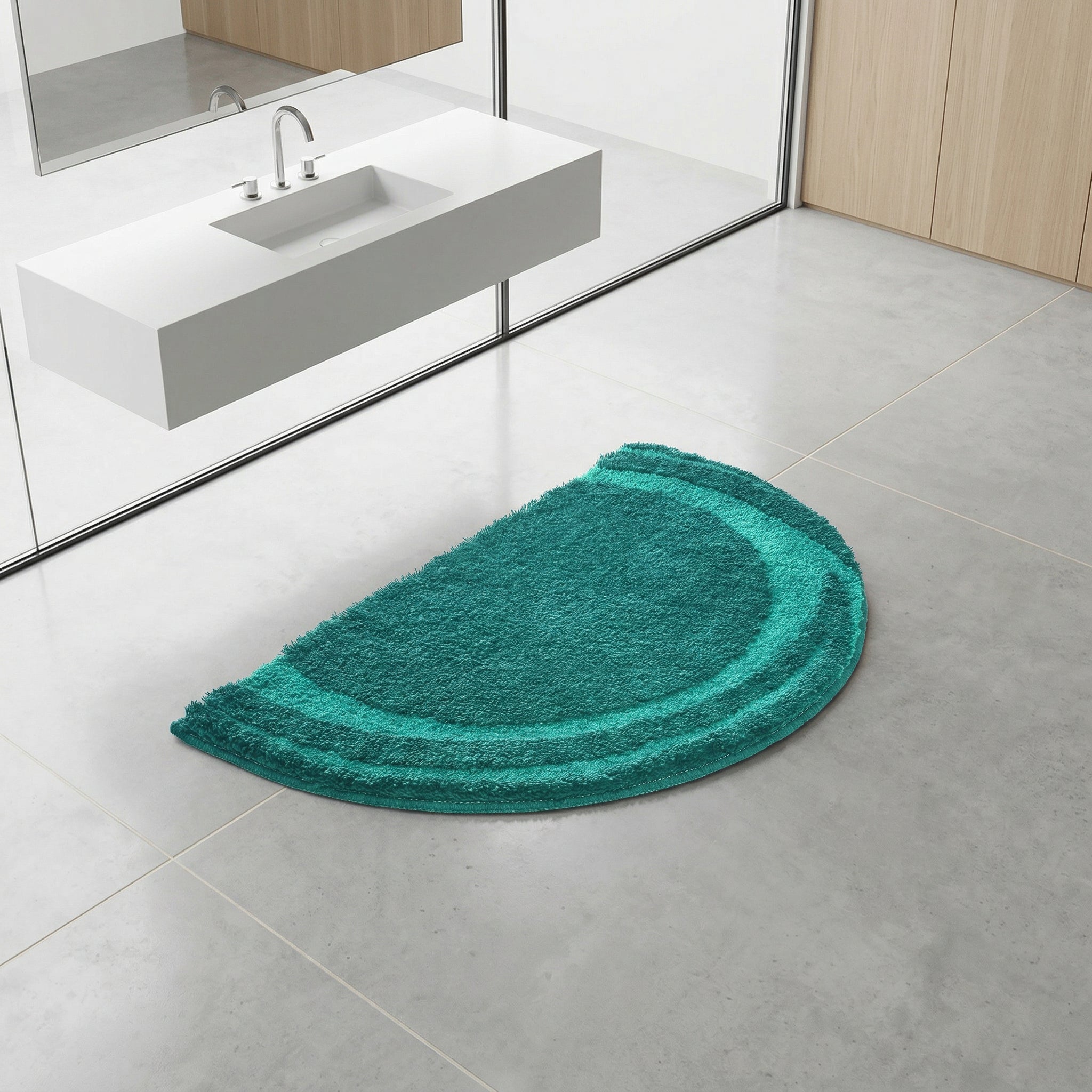 Halbrunder türkisfarbener Badezimmerteppich vor weißem Waschbecken