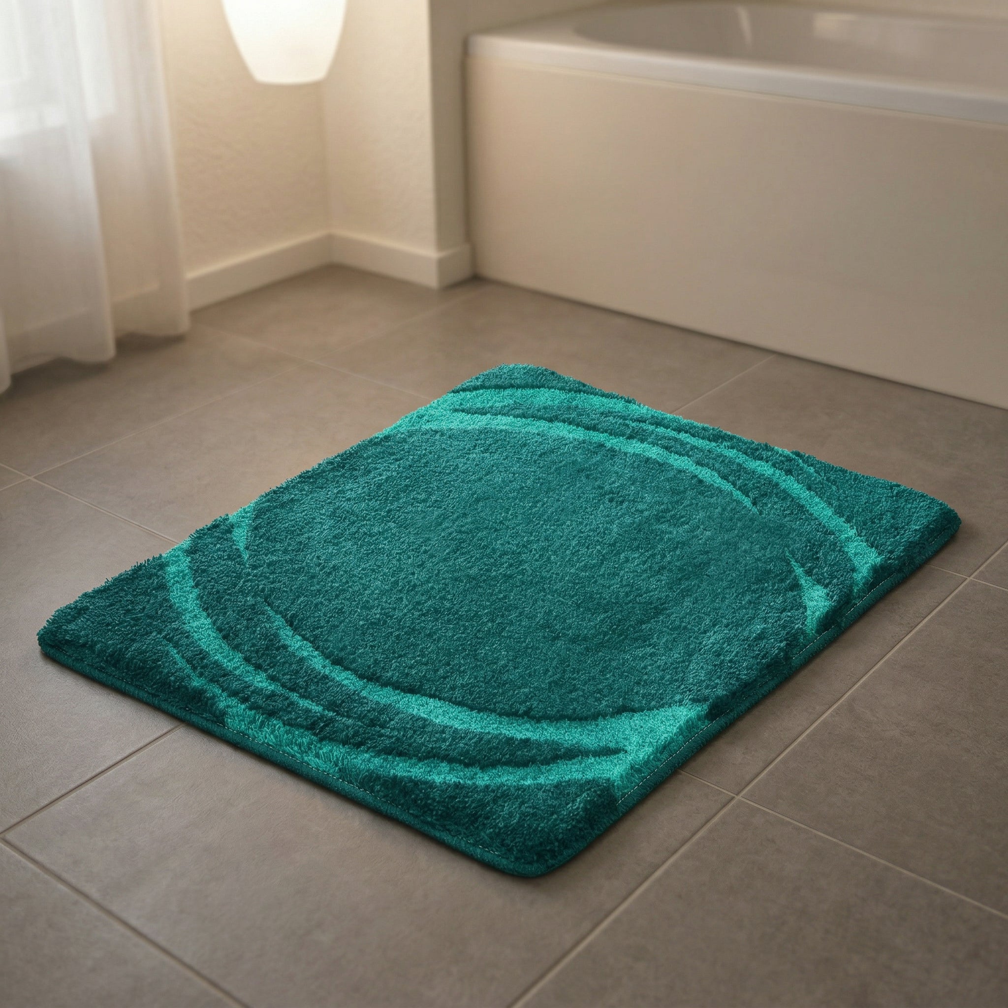 Türkisgrüne Badematte mit kreisförmigem Muster auf grauen Fliesen